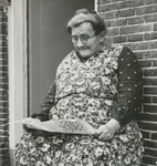 860985 Portret van mevr. Klinkenberg ('Door 't Nekkie'), die de krant leest voor haar woning (Kroonstraat 69) in Wijk C ...